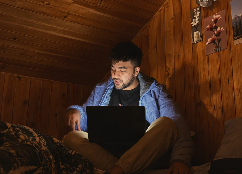 A Bricx teammate working on a laptop in a wood-panelled cabin