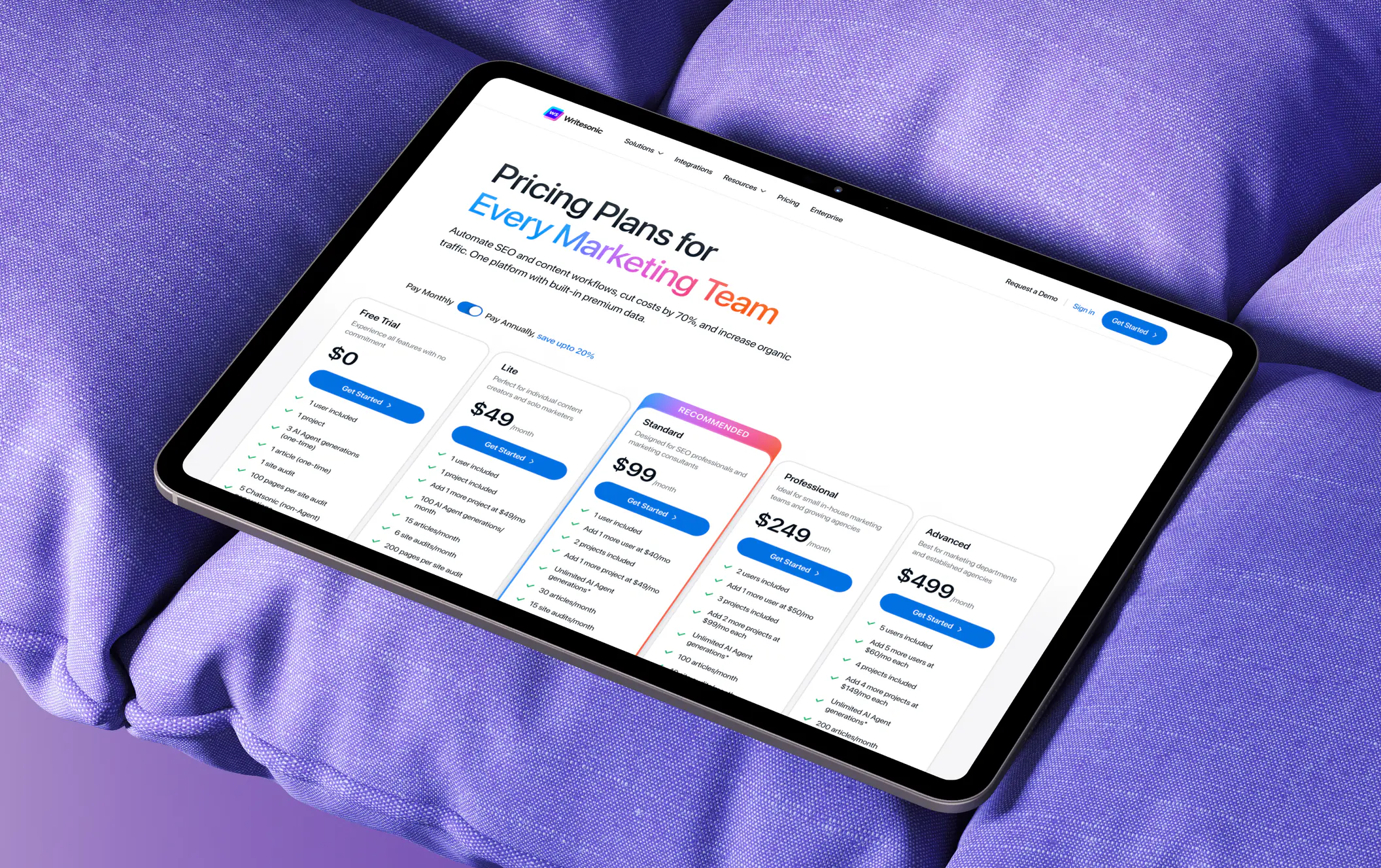Writesonic's pricing page on an iPad Pro, lying on a lavender cushion